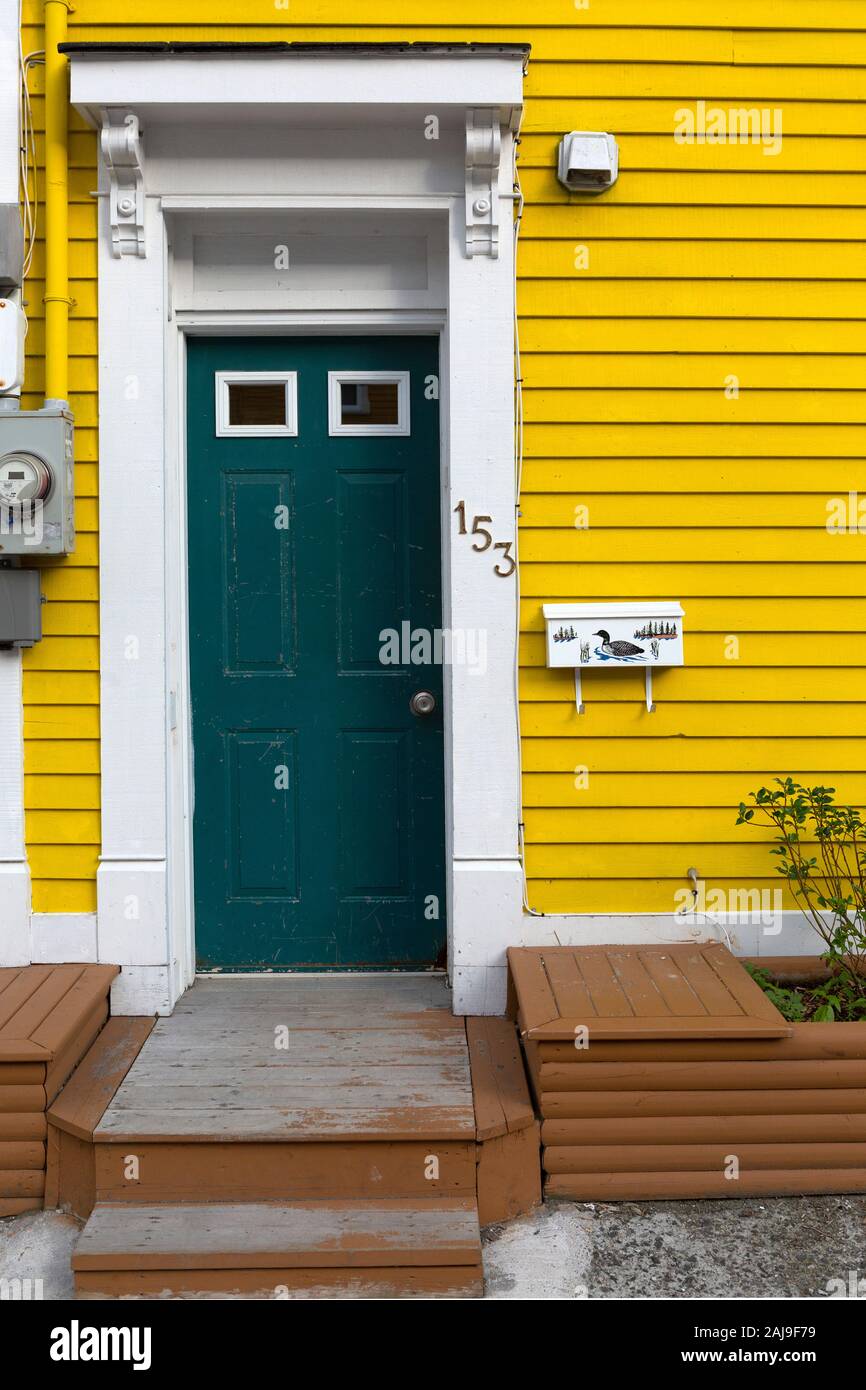 Facade of a yellow house in St John's, Newfoundland and Labrador, Canada. The house has a white door frame. Stock Photo