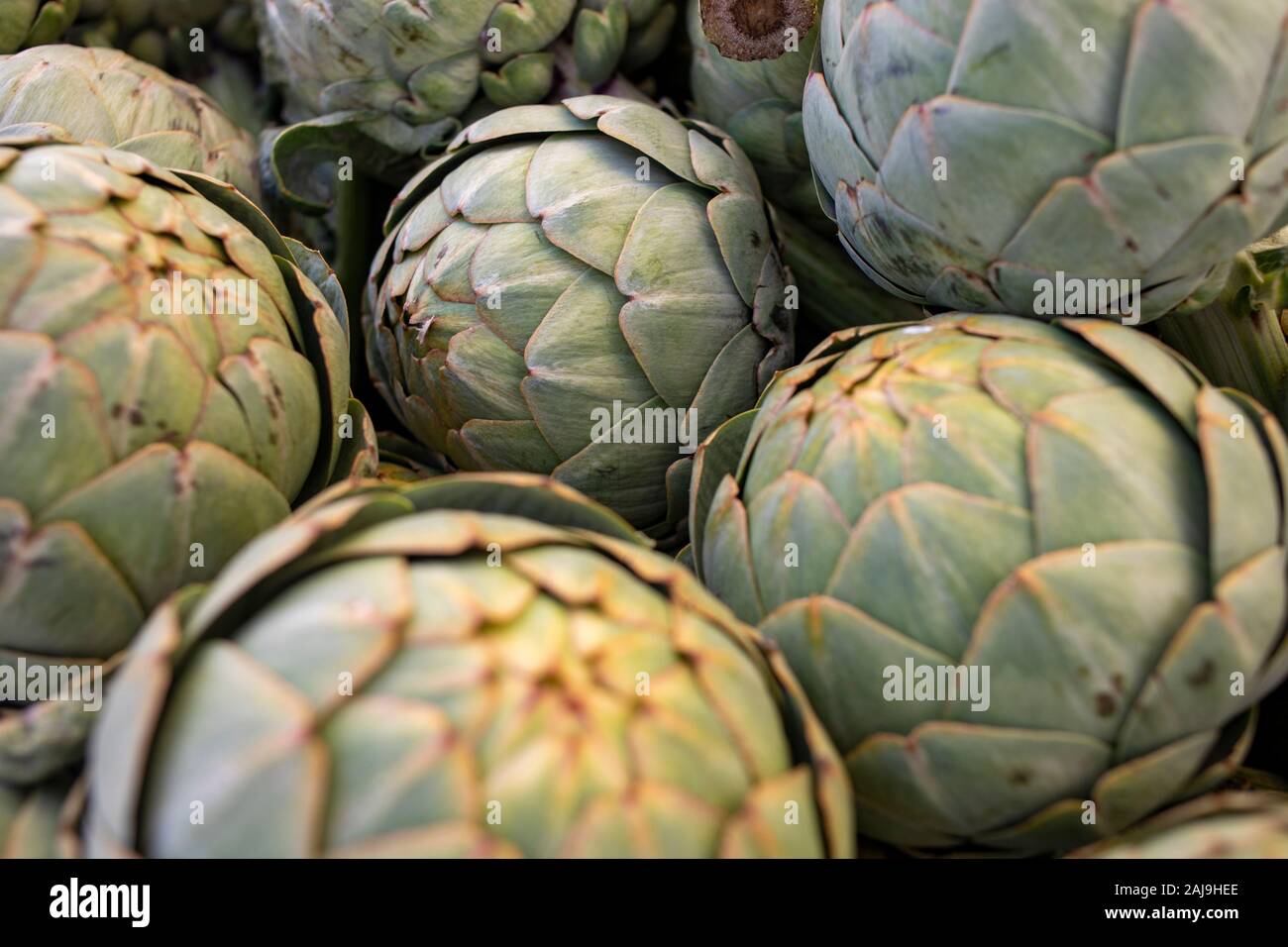 a pile of artichokes at a fruit and vegetable stand. Stock Photo