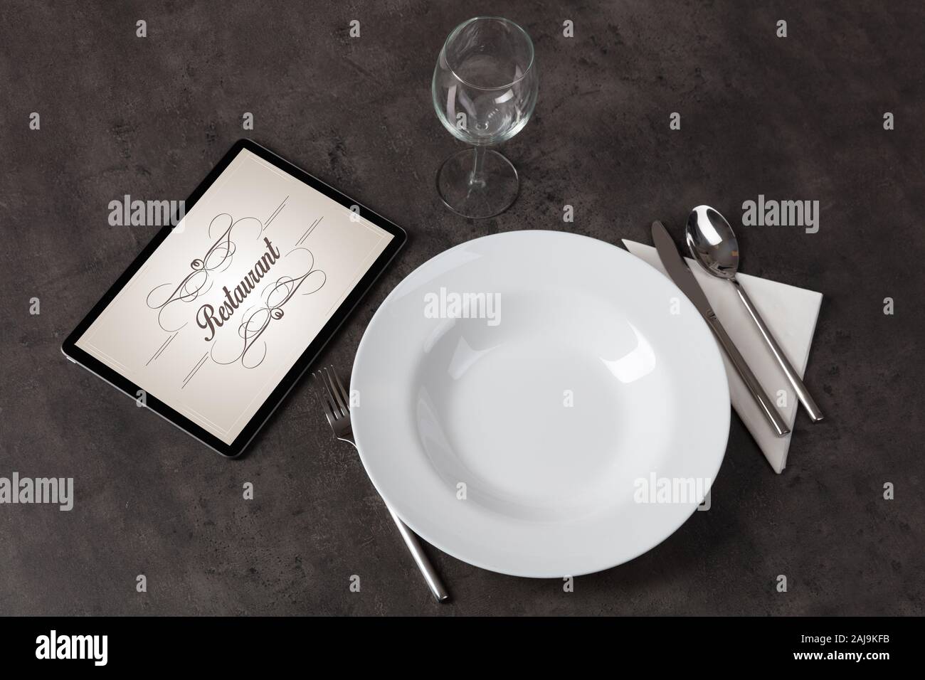 Tablet with stylish restaurant logo and laid table Stock Photo
