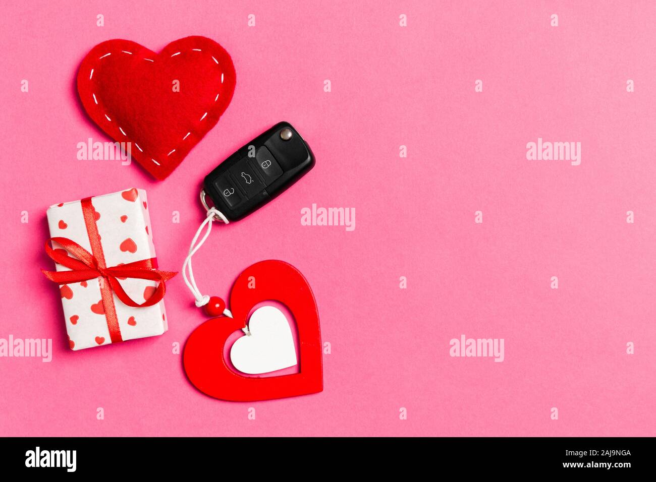 Top view of gift box, car key, wooden and textile heart on colorful