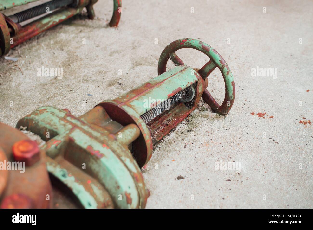 Rusted up industrial machinery tool on dirty concrete factory floor Stock Photo