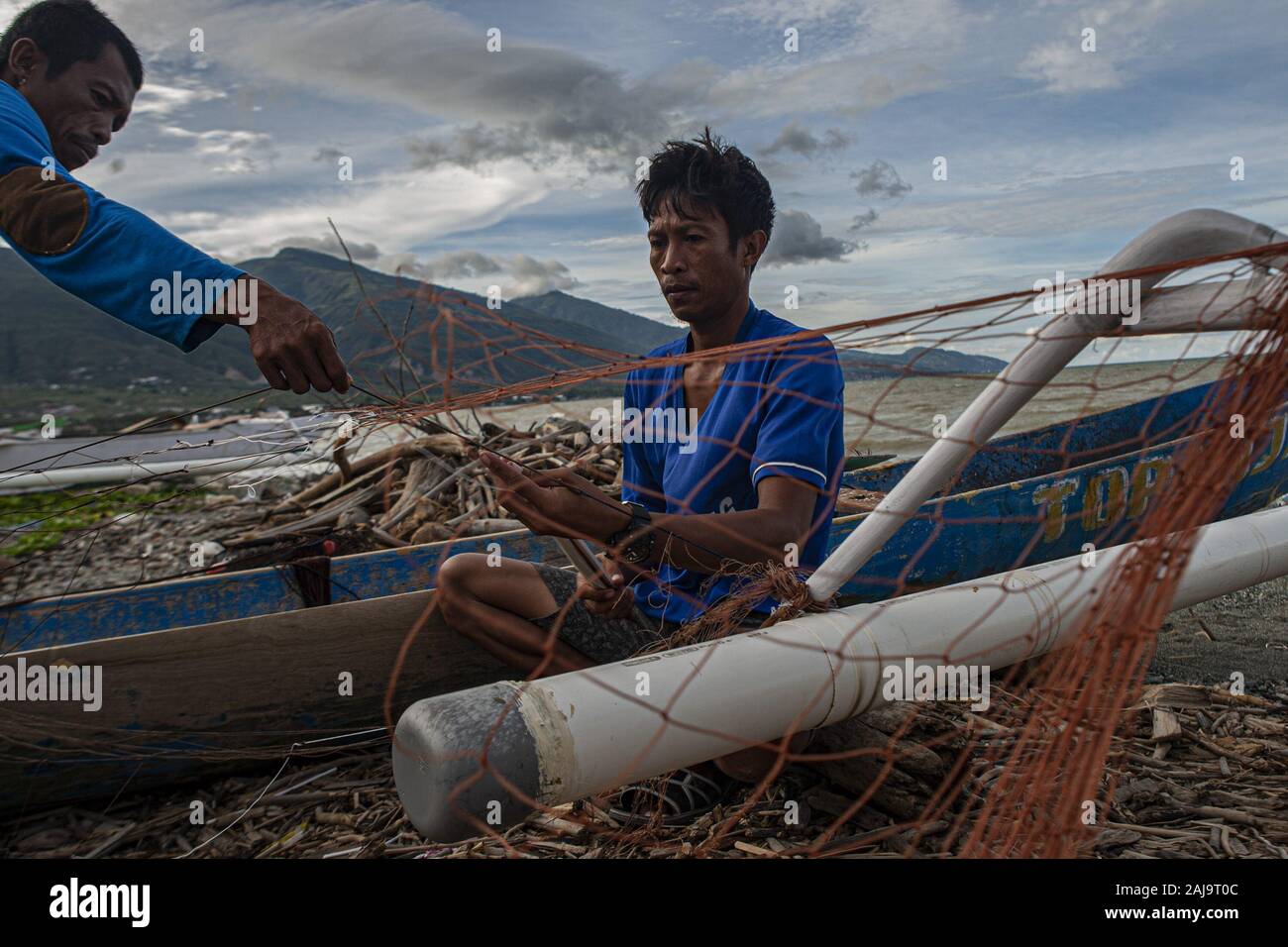 Palu City, Central Sulawesi, Indonesia. 3rd Jan, 2020. Two fishermen working on a torn fishing net.High waves in the waters of Palu Bay forced Hundreds of fishermen in the village of Lere to anchor their boats. According to the Palu Meteorology, Climatology and Geophysics Agency (BMKG) the waves reached two meters to three meters, considered quite dangerous for fishermen. Credit: Opan Bustan/SOPA Images/ZUMA Wire/Alamy Live News Stock Photo