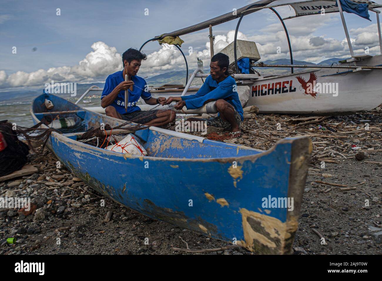 Palu City, Central Sulawesi, Indonesia. 3rd Jan, 2020. Two fishermen working on a torn fishing net.High waves in the waters of Palu Bay forced Hundreds of fishermen in the village of Lere to anchor their boats. According to the Palu Meteorology, Climatology and Geophysics Agency (BMKG) the waves reached two meters to three meters, considered quite dangerous for fishermen. Credit: Opan Bustan/SOPA Images/ZUMA Wire/Alamy Live News Stock Photo
