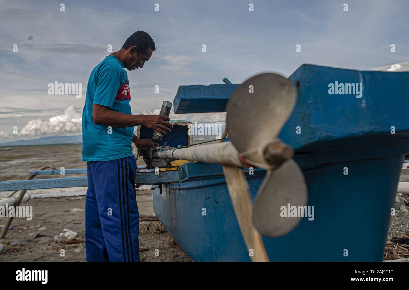 Palu City, Central Sulawesi, Indonesia. 3rd Jan, 2020. A fisherman fixes a broken boat engine.High waves in the waters of Palu Bay forced Hundreds of fishermen in the village of Lere to anchor their boats. According to the Palu Meteorology, Climatology and Geophysics Agency (BMKG) the waves reached two meters to three meters, considered quite dangerous for fishermen. Credit: Opan Bustan/SOPA Images/ZUMA Wire/Alamy Live News Stock Photo