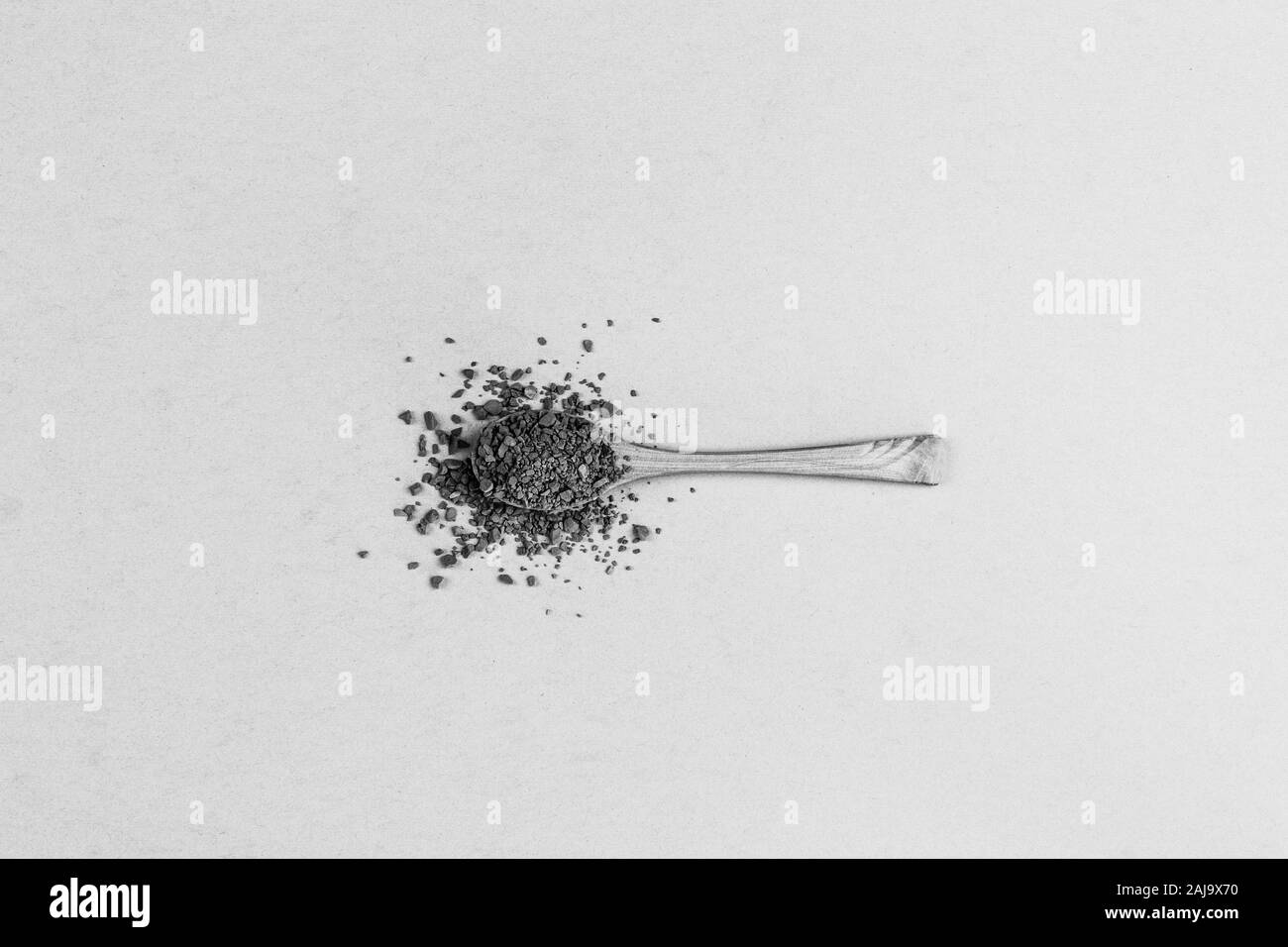 wooden spoon with instant granular coffeeon grey background top view, black and white photo, minimal art Stock Photo