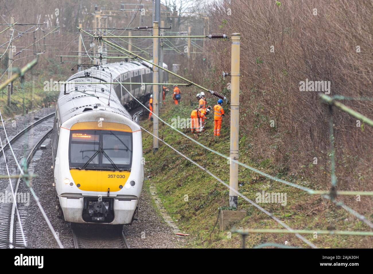 RailScape workers cutting back vegetation close to the track of the C2C railway in Southend on Sea, Essex, UK. Permanent way crew with train passing Stock Photo
