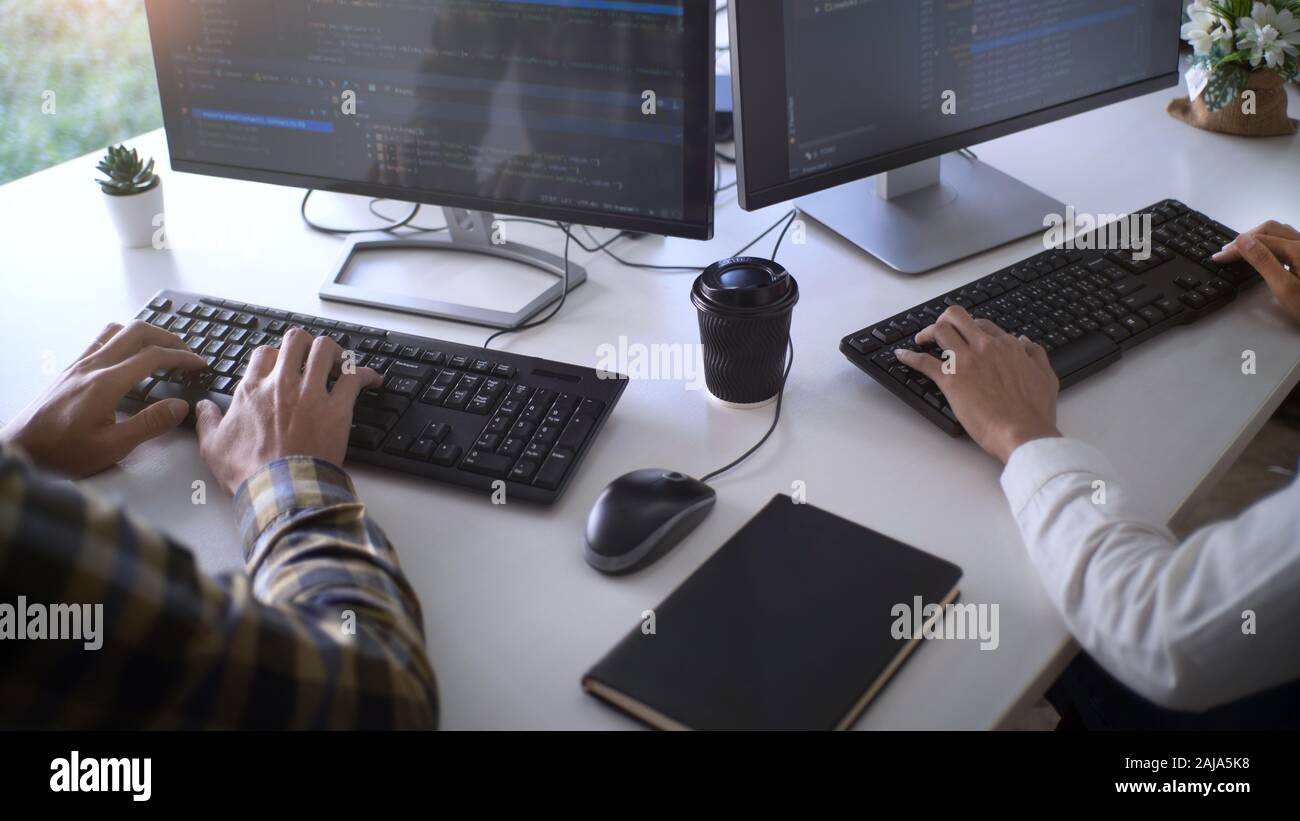 Young startup Programmers Sitting At Desks Working On Computers screen for Developing programming and coding to find solution to problem on New Applic Stock Photo