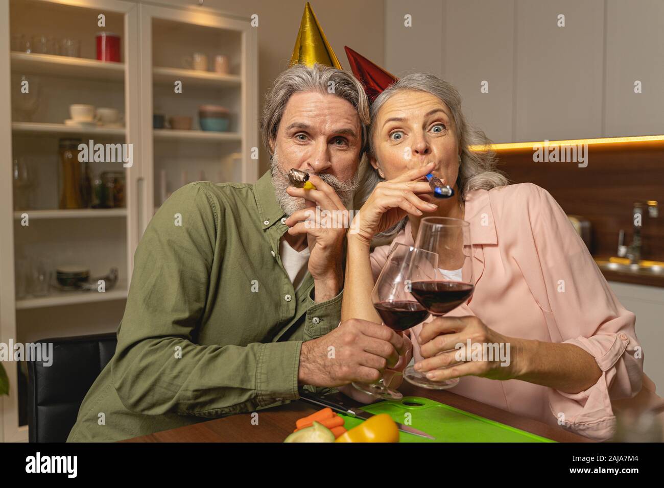 Husband and a wife blowing party horns Stock Photo - Alamy