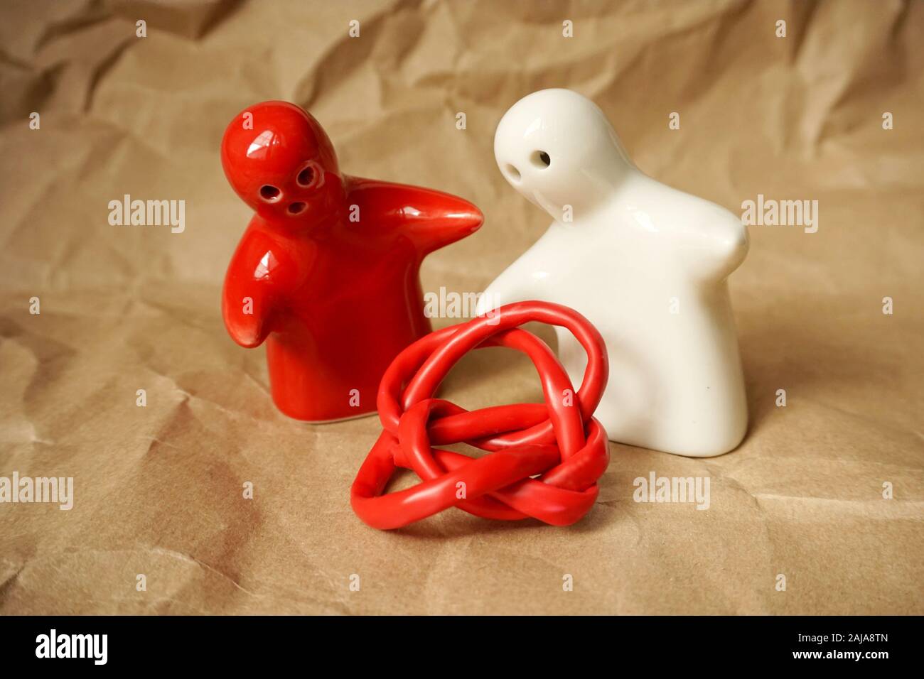 Tangled red wire between two ceramic figurines as humans with free copy space Stock Photo