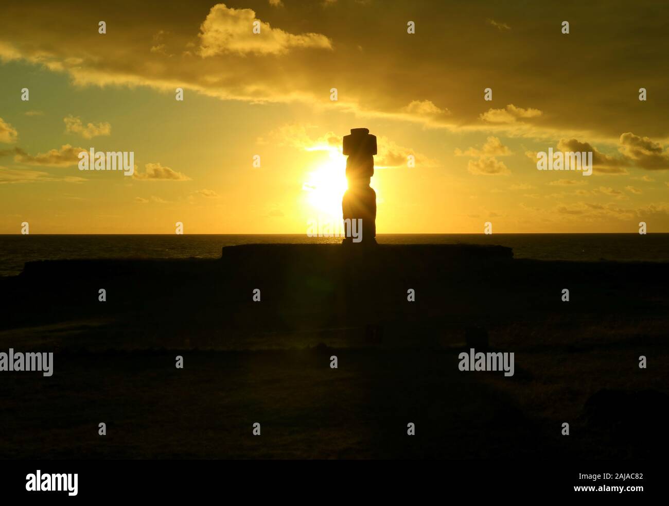 The setting sun shining through Moai's silhouette at Ahu Tahai , Easter Island, Chile Stock Photo
