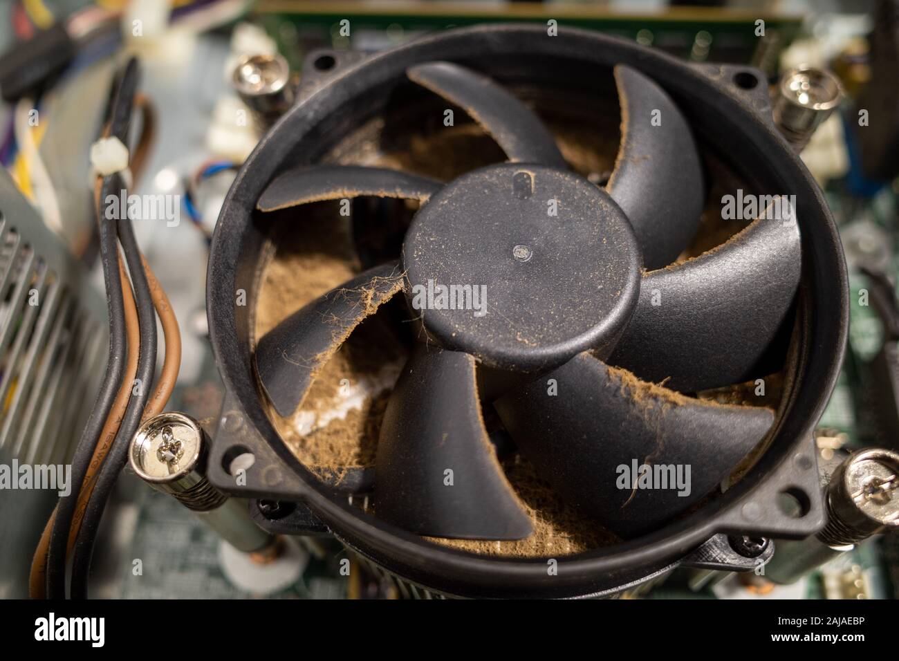 a very dirty computer fan inside a computer is cleaned by a vacuum
