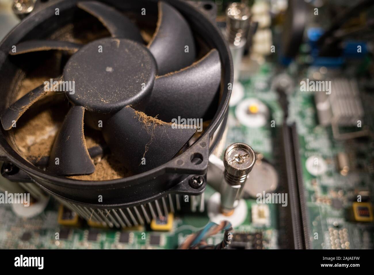 a very dirty computer fan inside a computer is cleaned by a vacuum