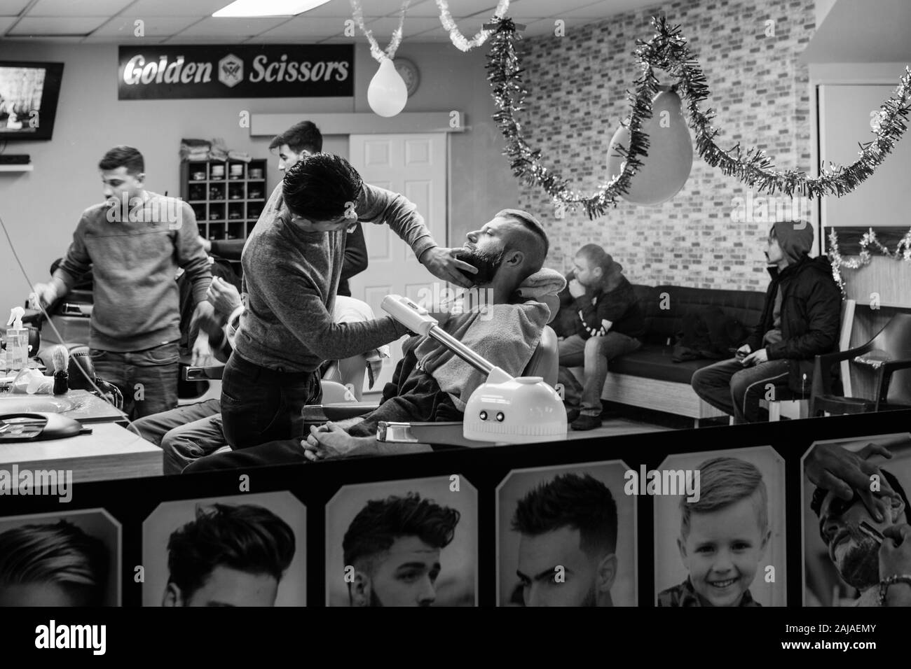 Street scene of traditional Turkish barber shop window with client having beard trimmed with cut throat razor. unsharpened Stock Photo