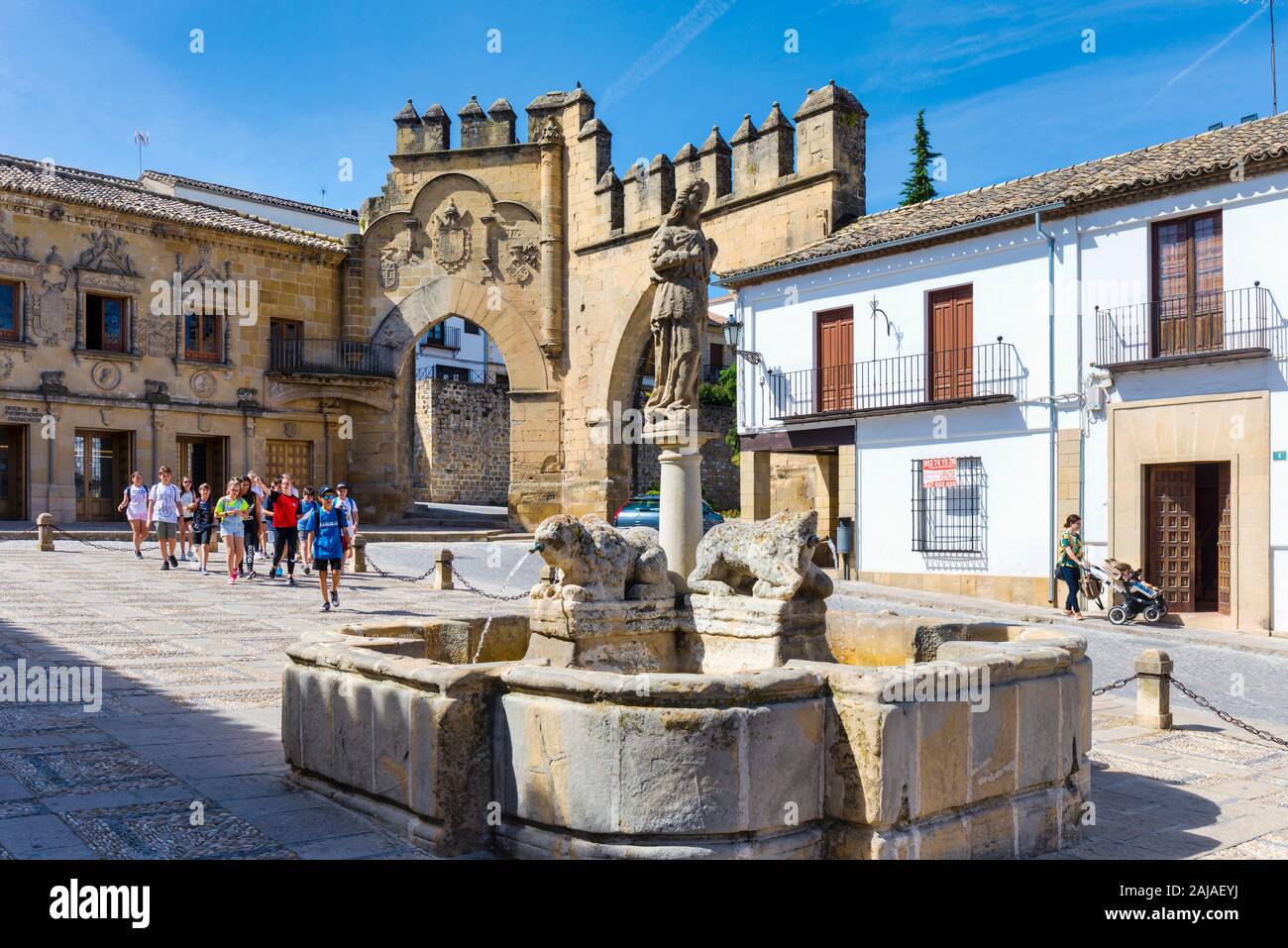 Fuente de los Leones, or Fountain of the Lions, in the Plaza del Populo, Baeza, Jaen Province, Andalusia, Spain.  The ornamental city gate in the back Stock Photo
