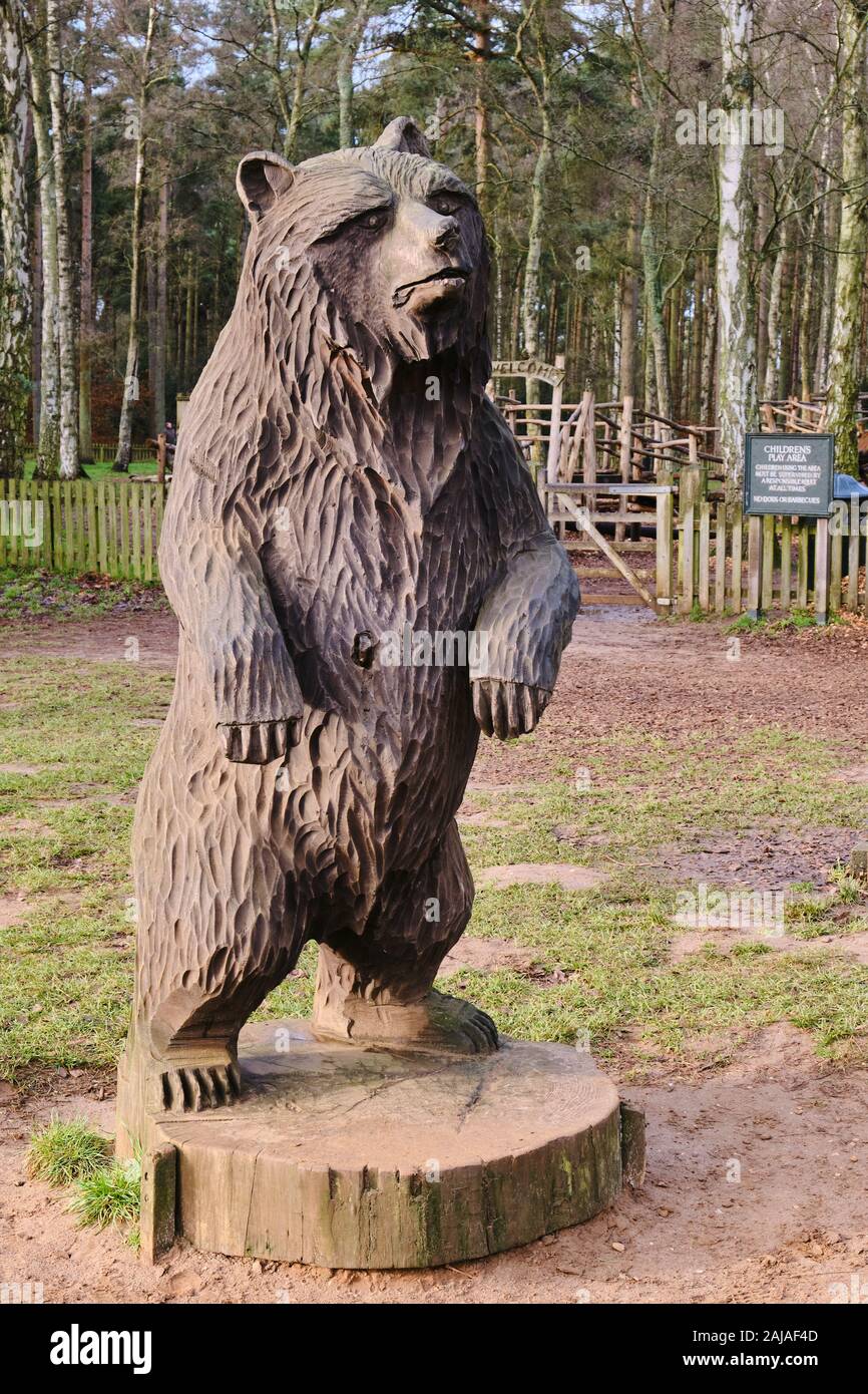 Carved wooden sculpture carving of a bear by trail in woodland at Sandringham in Norfolk Stock Photo