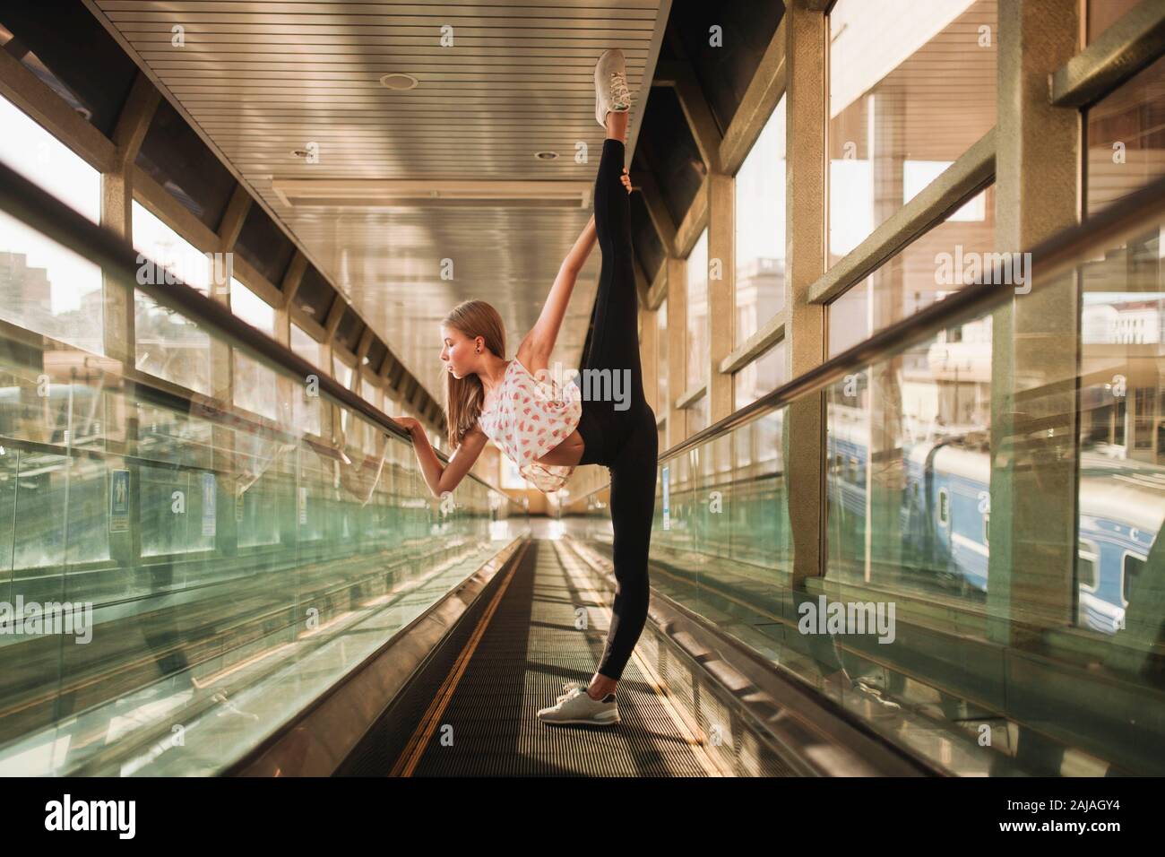 woman ballerina stands in a tunnel lifting her leg high Stock Photo