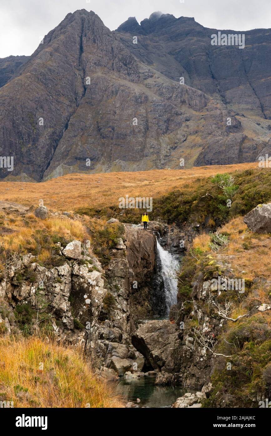 Fairy Pools Isle of Skye with Black Cuillin mountains behind and tourist posing for photo at top of waterfall, Scotland, UK Stock Photo