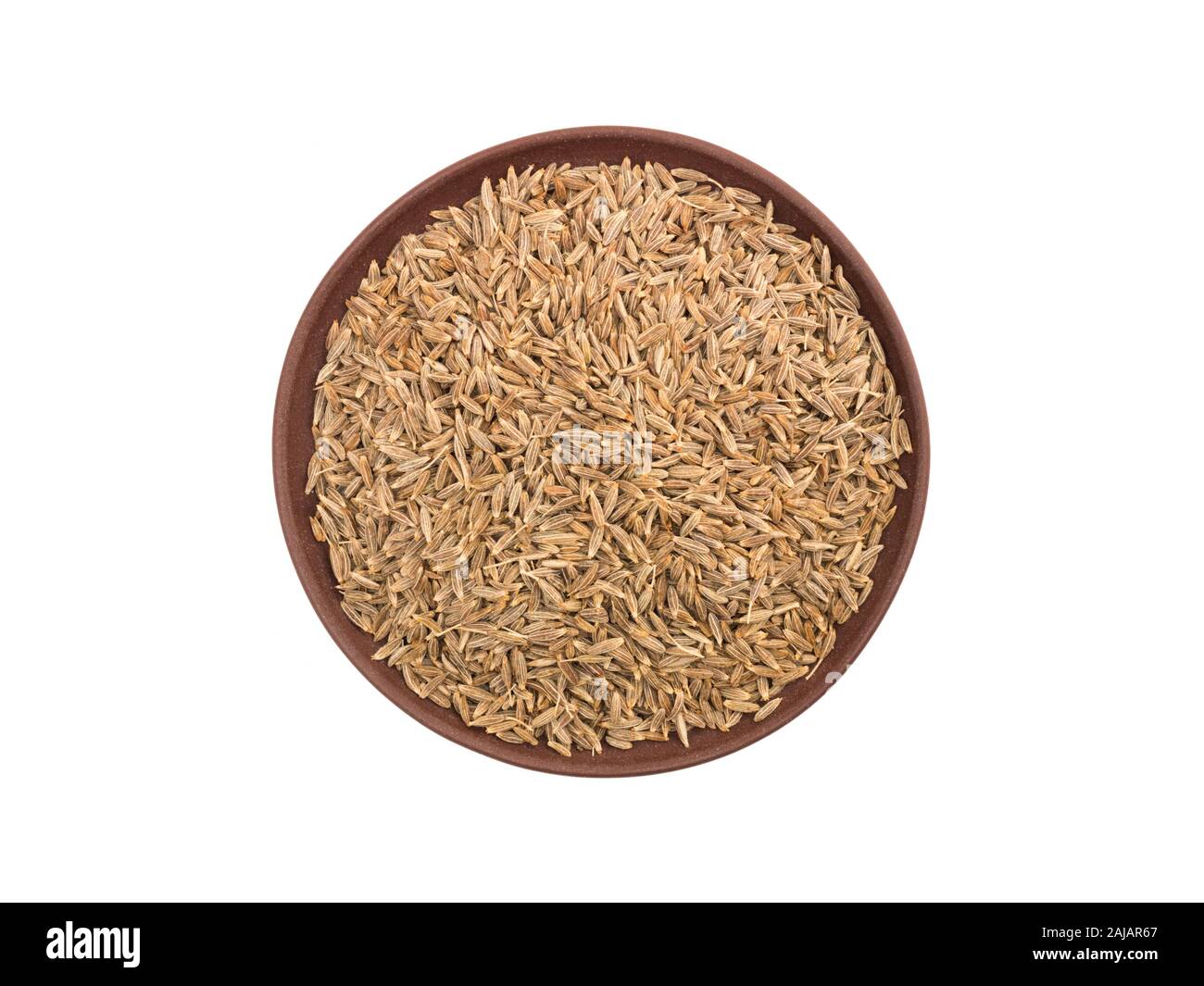Spices cumin (jeera) in clay plate on white isolated background. Indian
