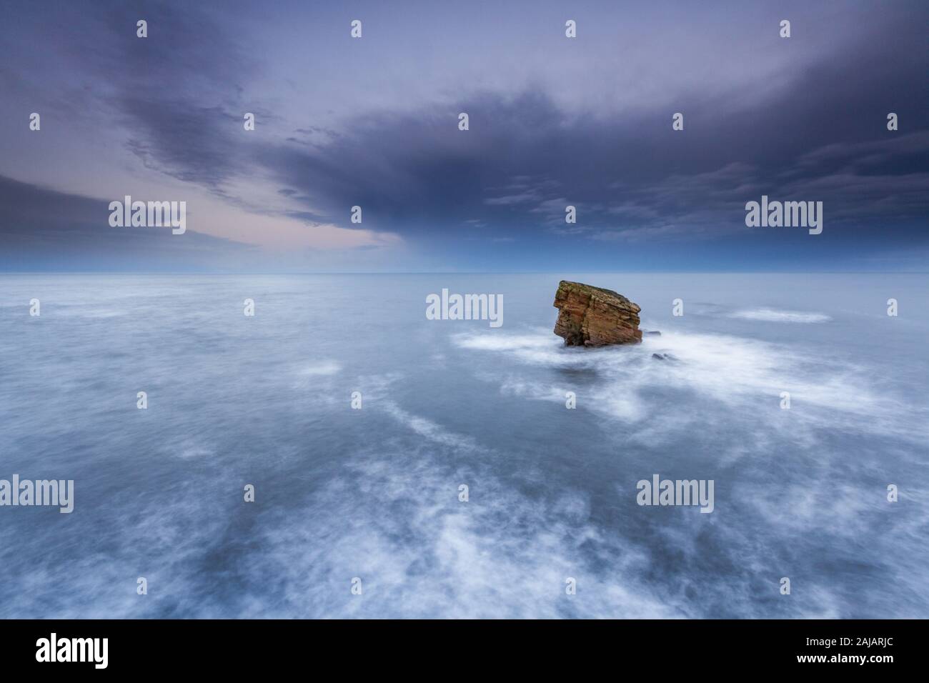 A single sea stack out at sea after the storm at sunset, Charlie's Garden at Collywell Bay, Northumberland Stock Photo