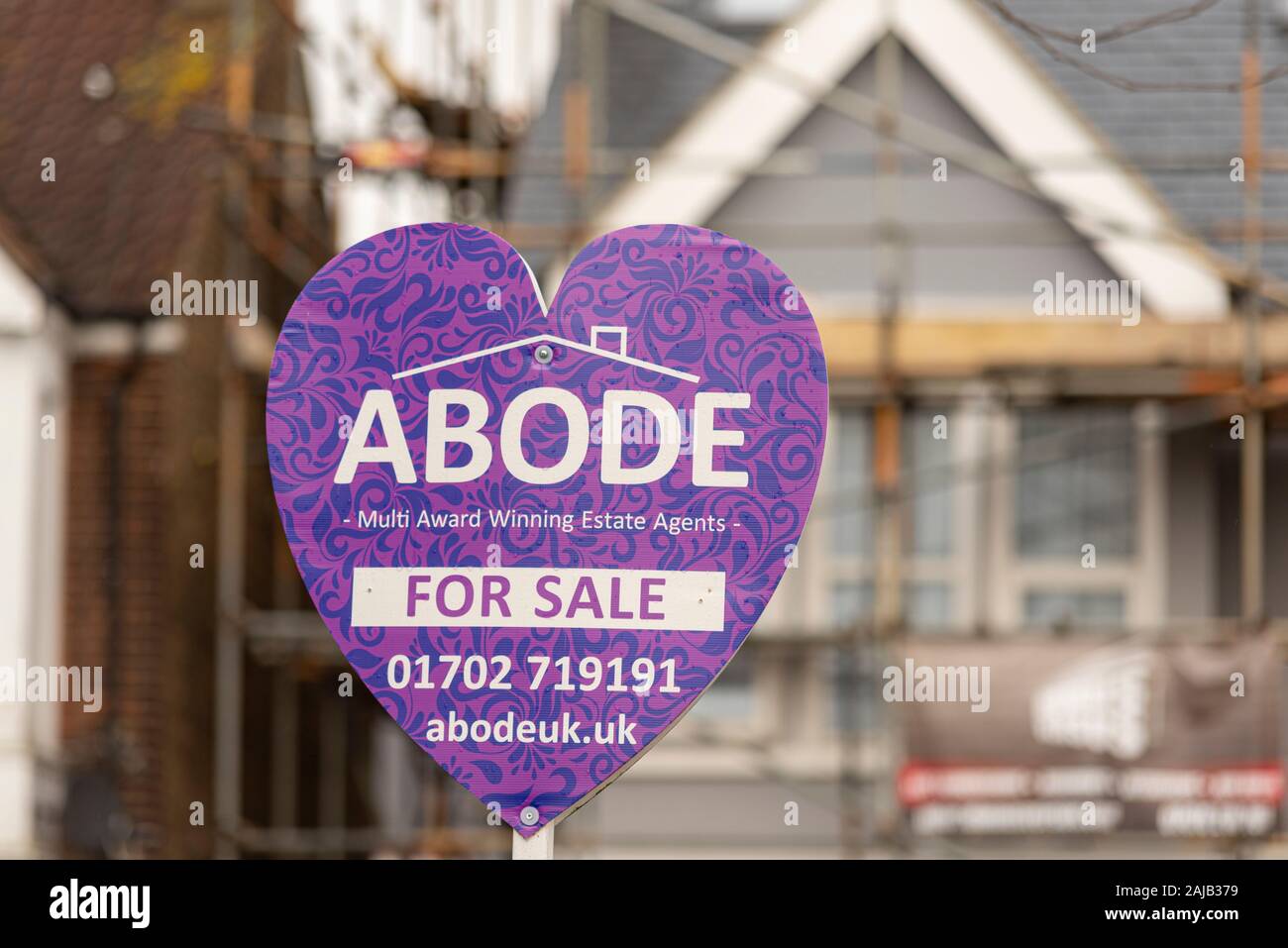 Abode estate agent property for sale sign Southend on Sea, Essex, UK with home behind with scaffolding. Southend phone number. Sign board heart shape Stock Photo