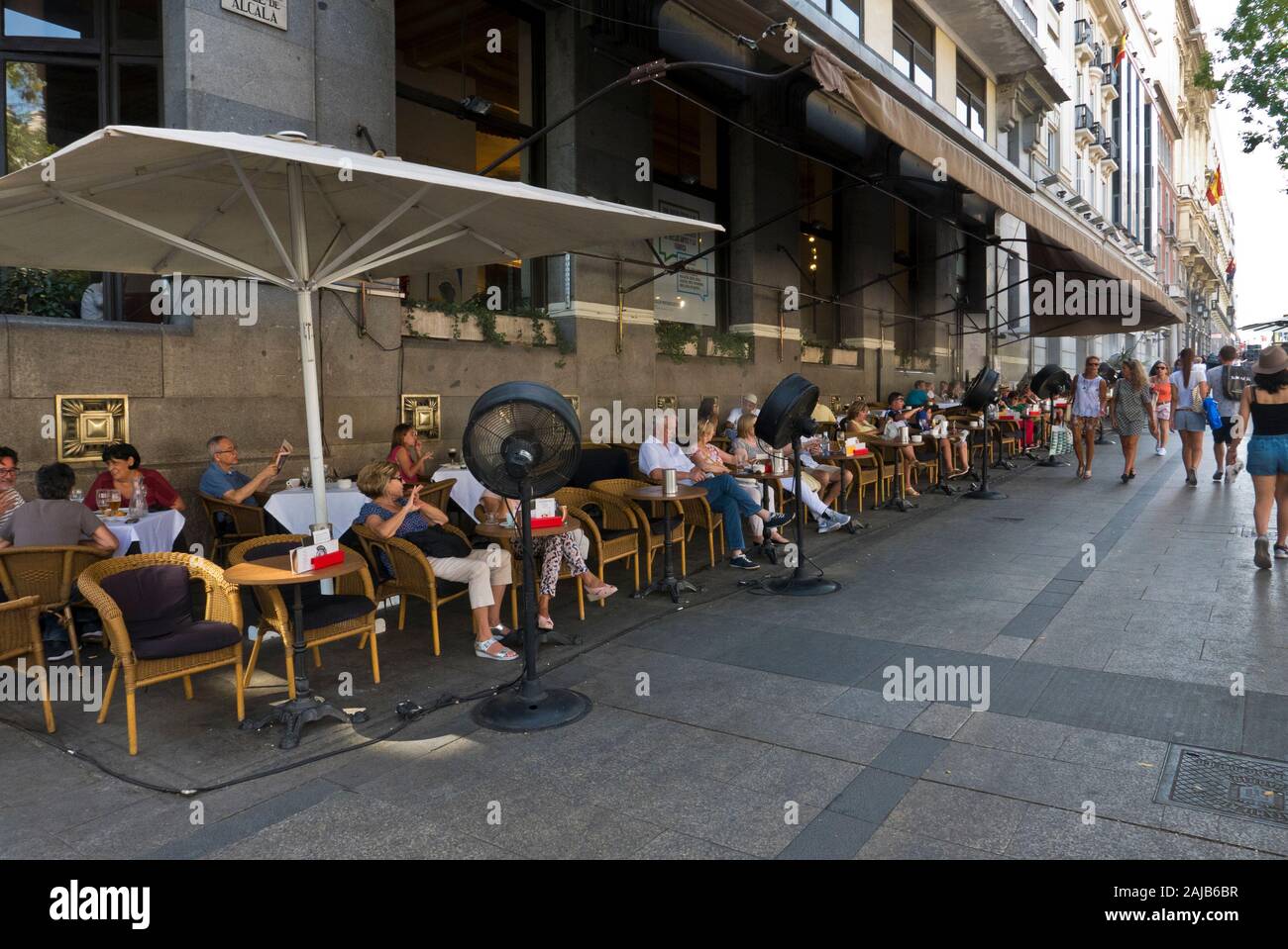 People sitting outside on street pavement relaxing in Madrid, Spain Stock Photo