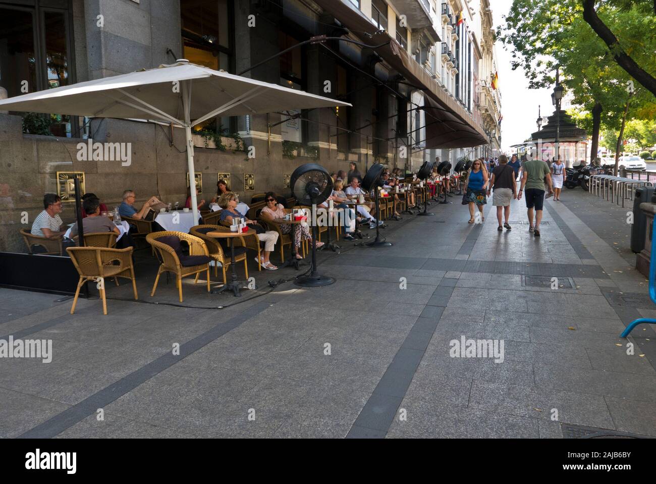 People sitting outside on street pavement relaxing in Madrid, Spain Stock Photo