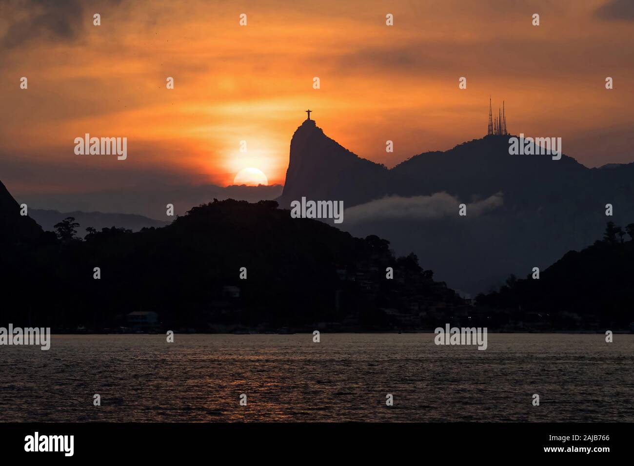 Sun setting behind the famous Christ the Redeemer statue atop the Corcovado Mountain in Rio de Janeiro, Brazil. Stock Photo