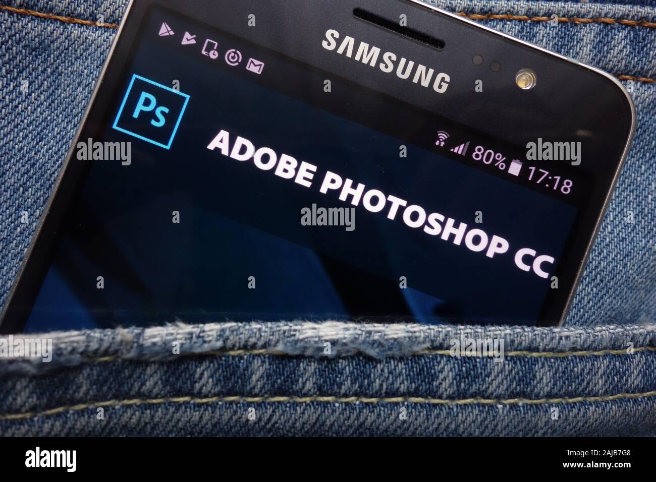 Adobe Photoshop website displayed on Samsung smartphone hidden in jeans pocket Stock Photo