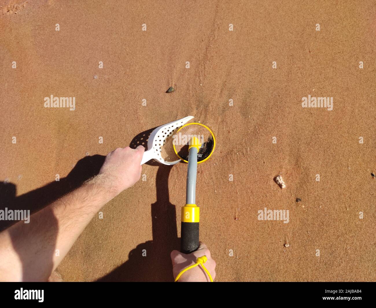 The photo of an underwater metal detector and a shovel on the sand ...