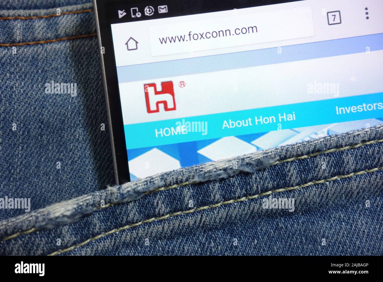 Foxconn website displayed on smartphone hidden in jeans pocket Stock Photo
