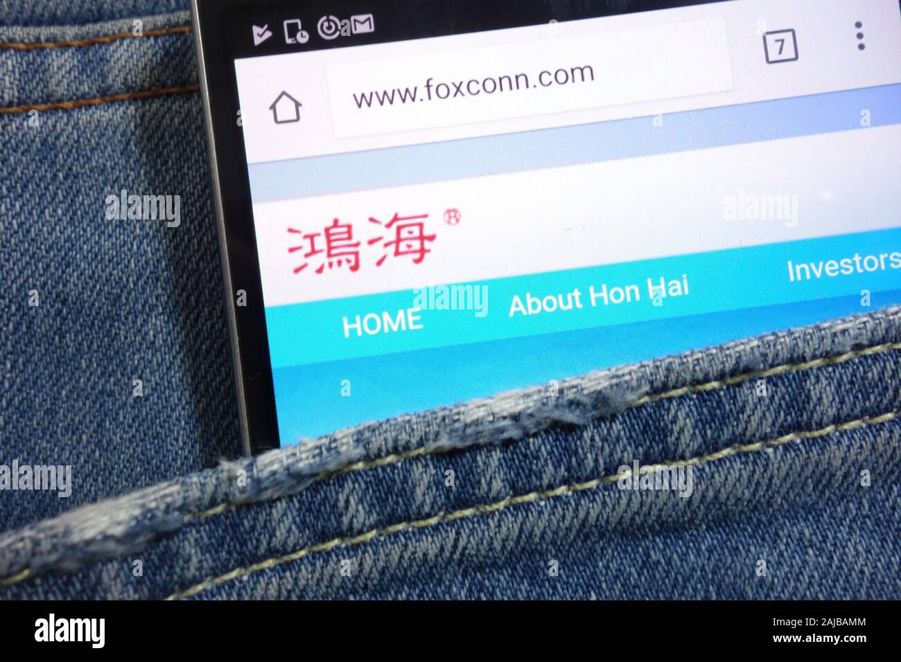 Foxconn website displayed on smartphone hidden in jeans pocket Stock Photo