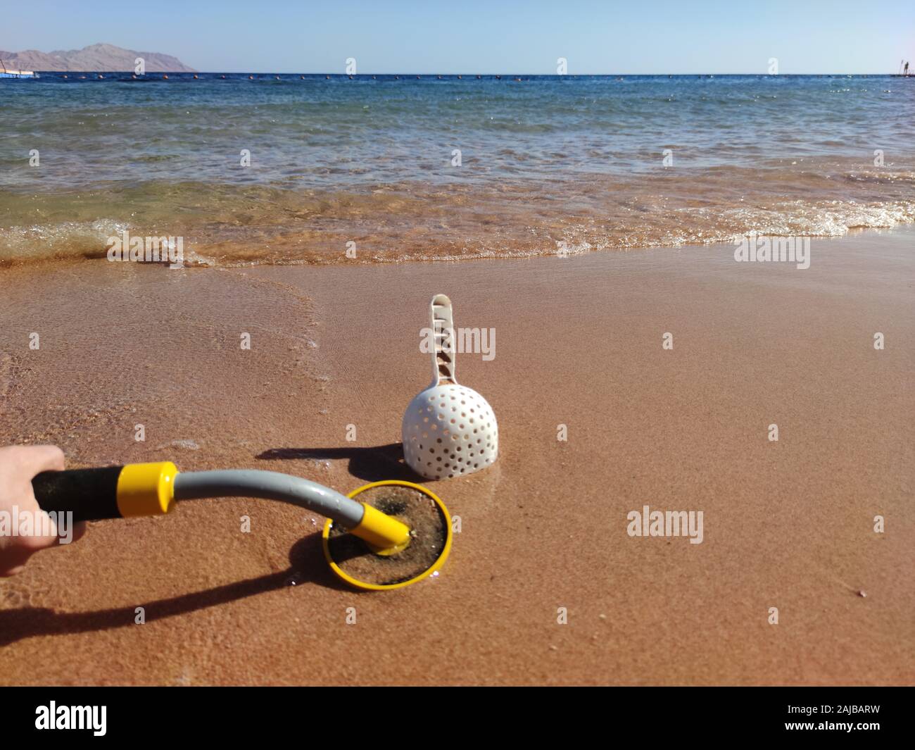The photo of an underwater metal detector and a shovel on the sand ...