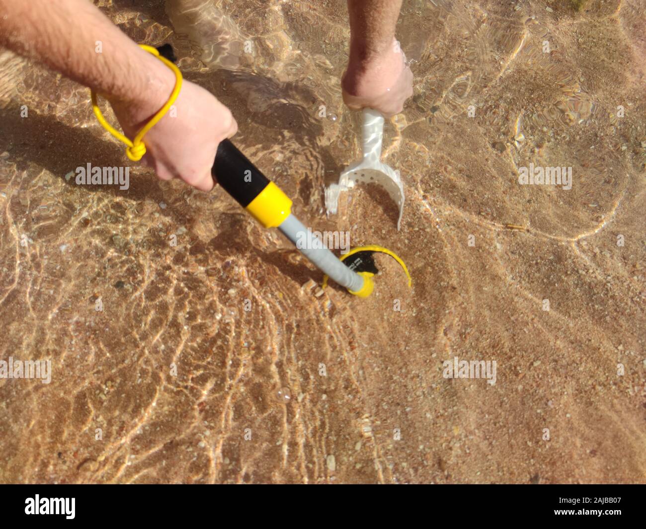The photo of an underwater metal detector and a shovel on the sand.Treasure searching and tourist adventure background. Stock Photo