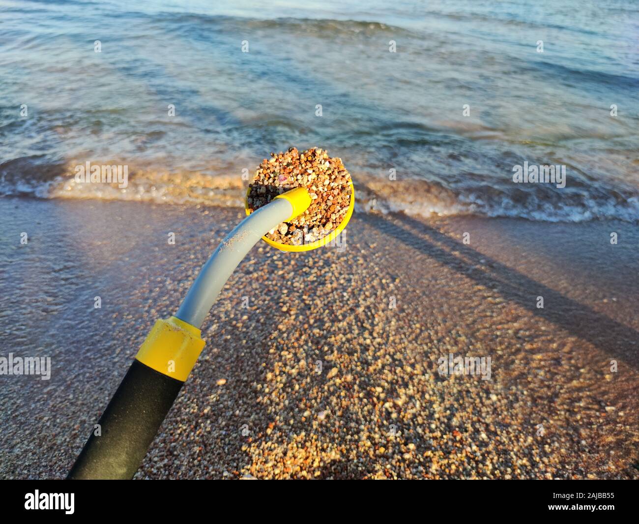 The photo of an underwater metal detector and a shovel on the sand ...