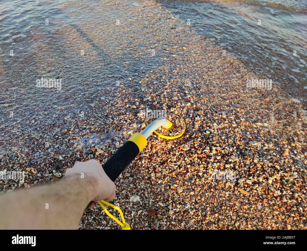 The photo of an underwater metal detector and a shovel on the sand ...