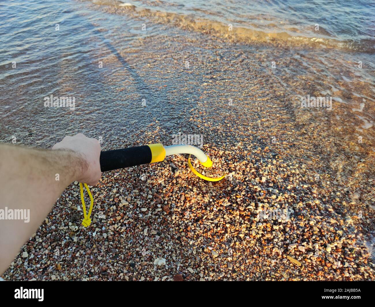 The photo of an underwater metal detector and a shovel on the sand ...