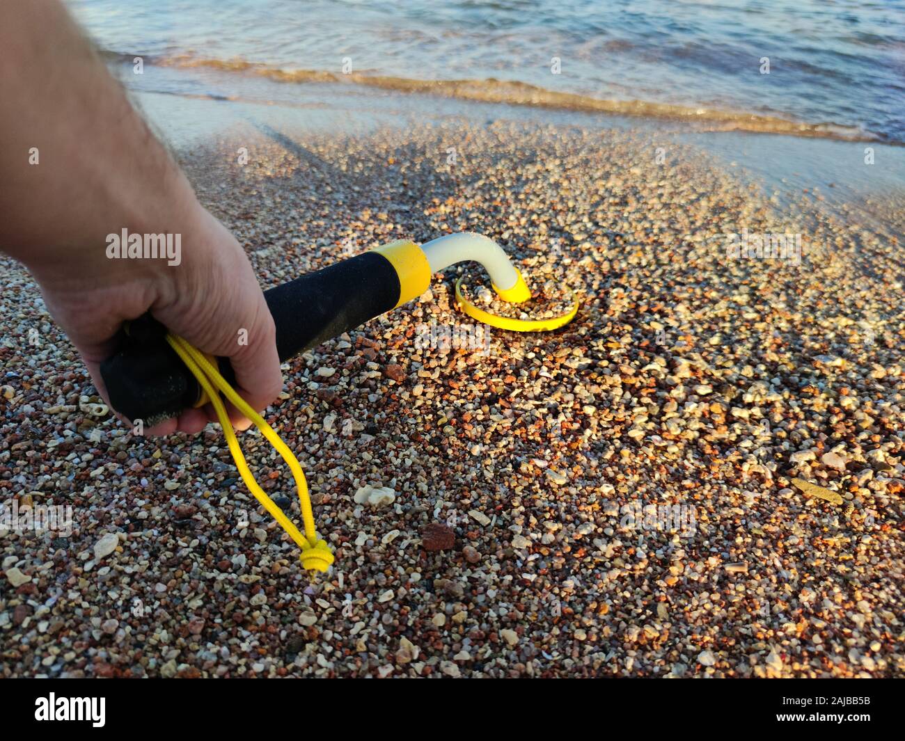 The photo of an underwater metal detector and a shovel on the sand ...