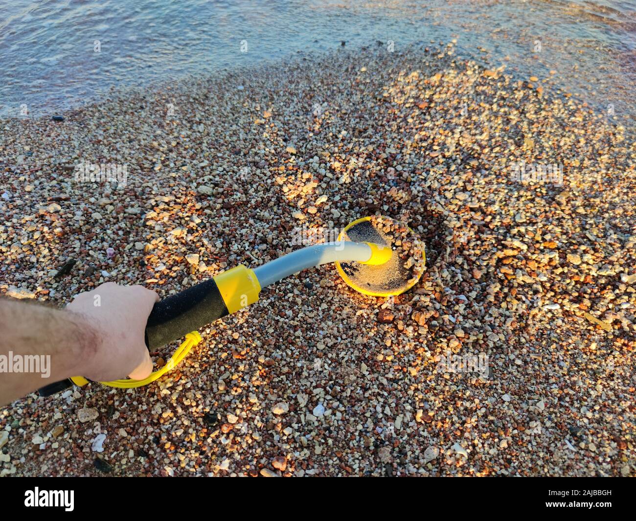 The photo of an underwater metal detector and a shovel on the sand ...