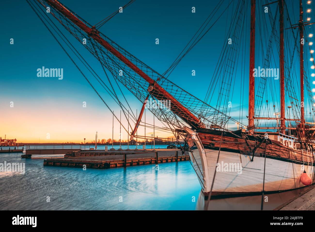 Helsinki, Finland. Old Wooden Sailing Vessel Ship Schooner Is Moored To City Pier, Jetty. Lighting At Evening Or Night Illumination. Stock Photo