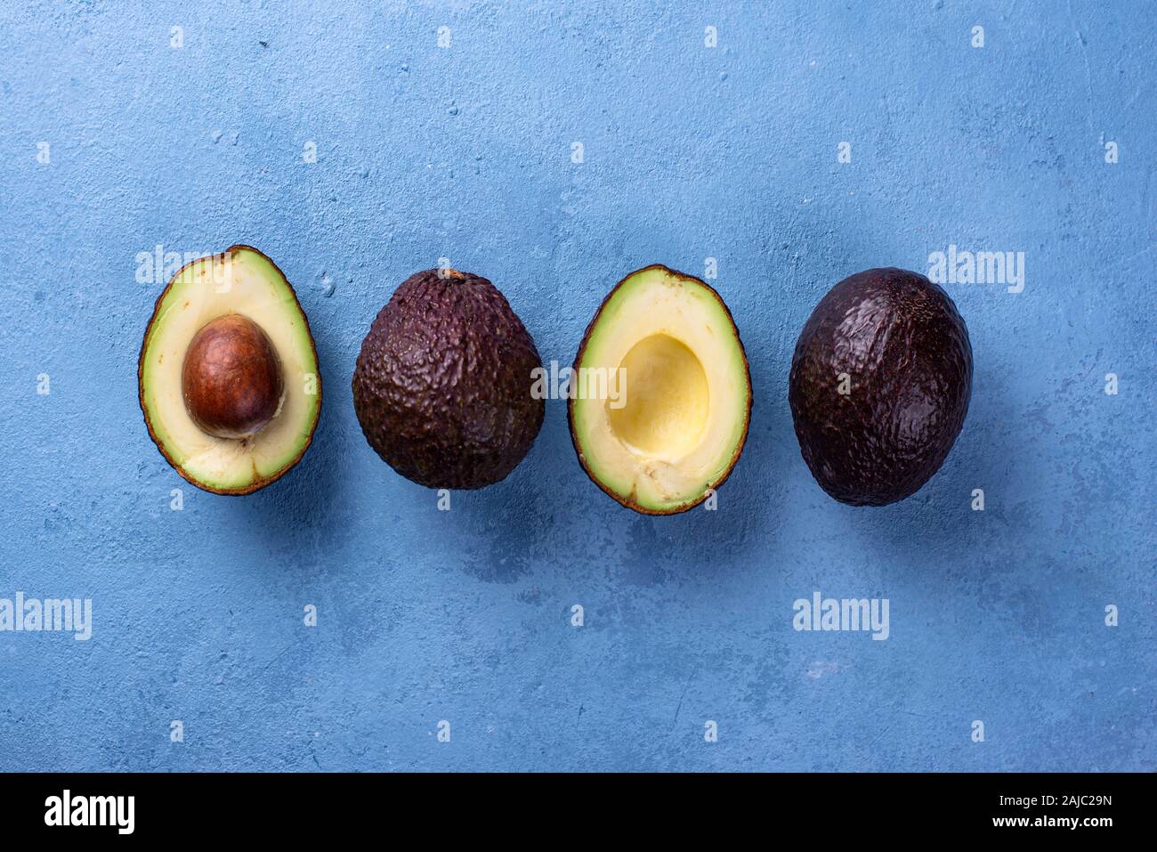 Half and whole avocado on blue background Stock Photo