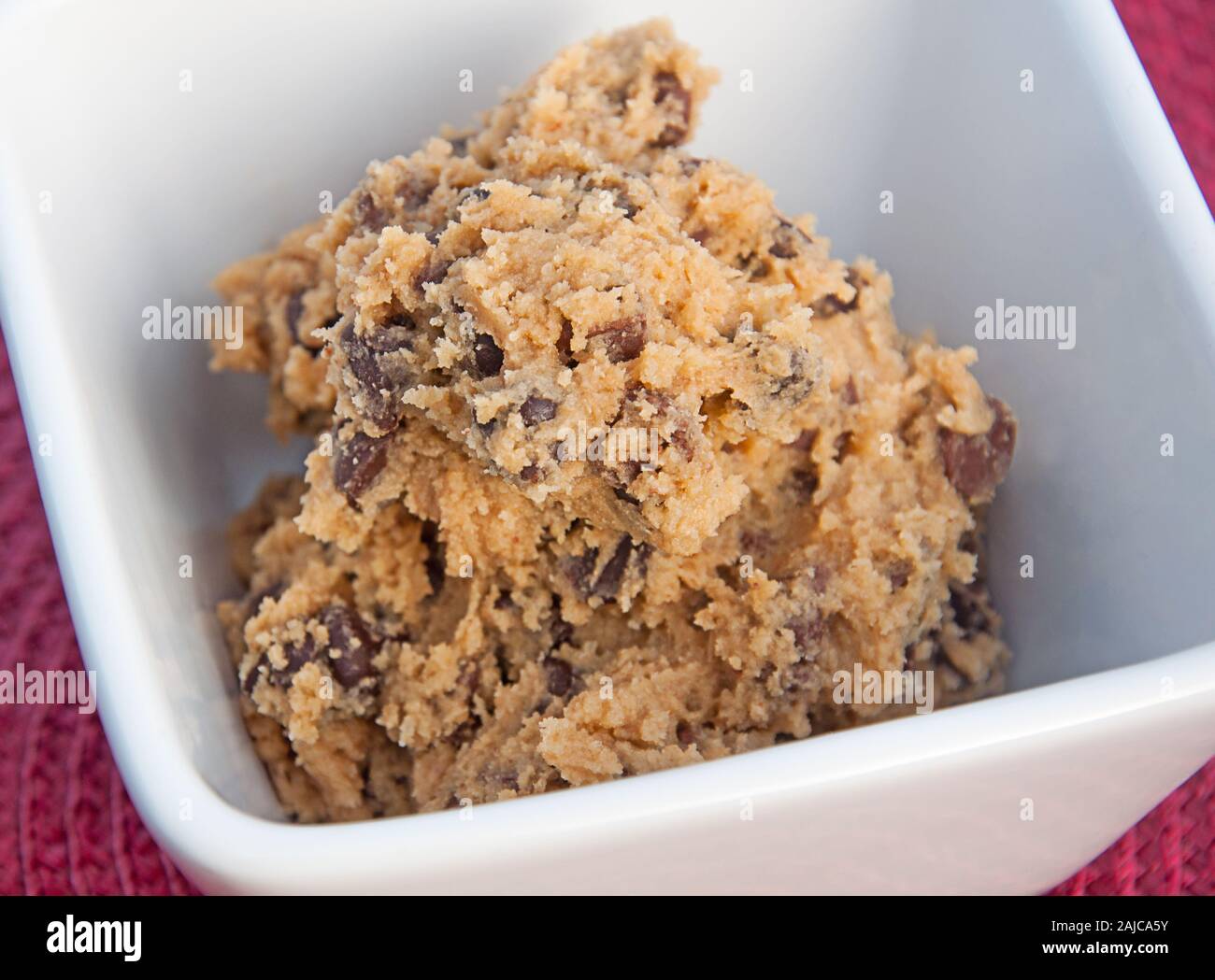 Chocolate chip cookie dough closeup in a white bowl.  This dessert food ingredient is ready to be baked for cookies.  Homemade cookie dough. Stock Photo