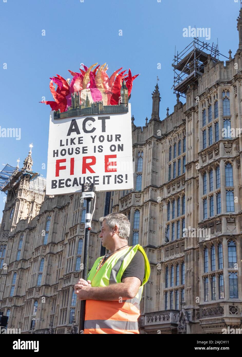 London / UK - September 20th 2019 - Climate change activist holds a sign saying Act Like Your House Is On Fire Because It Is outside Parliament in Wes Stock Photo