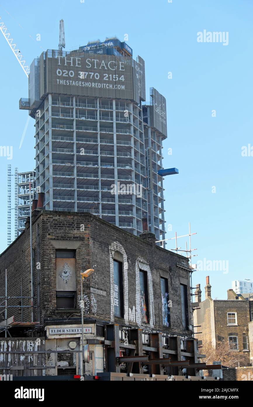 The Stage high rise tower property development under construction vertical view with derelict building Commercial Street East London E1  KATHY DEWITT Stock Photo
