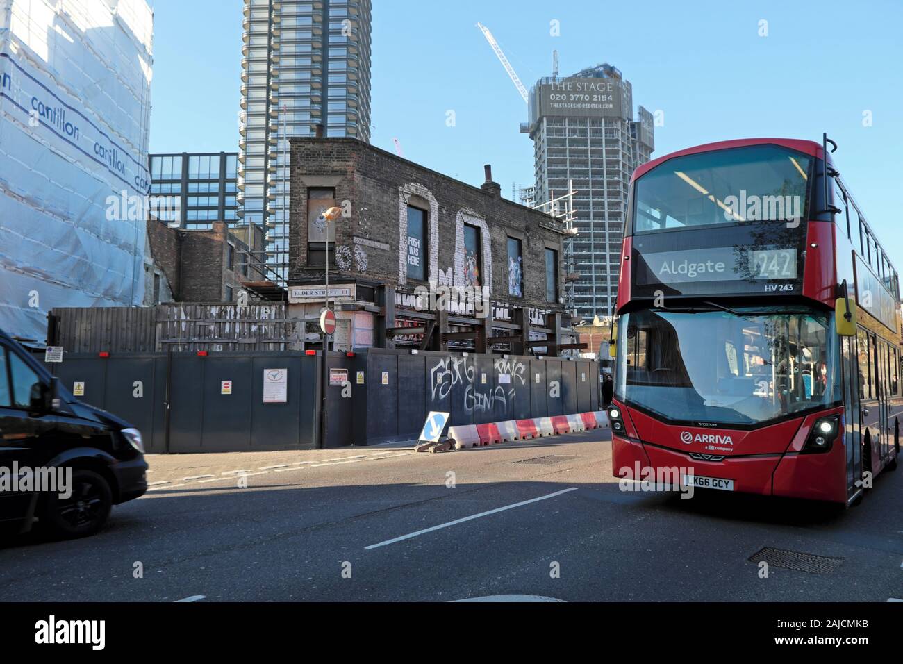 View of derelict building, Principal Place & The Stage residential tower under construction & red bus from Commercial Street London E1  KATHY DEWITT Stock Photo
