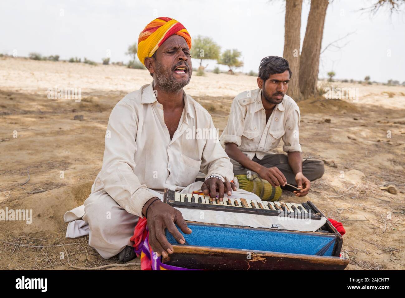 Jaisalmer, India - March 09 2017: A man plays a musical instrument and sings in the desert. Stock Photo