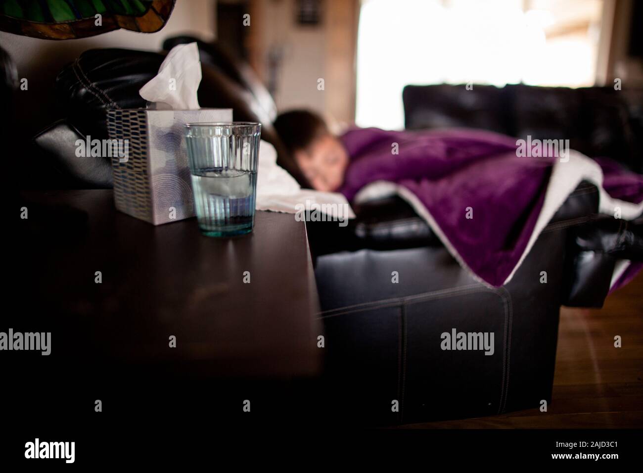 Side angle shot of blurred out sick boy on couch Stock Photo