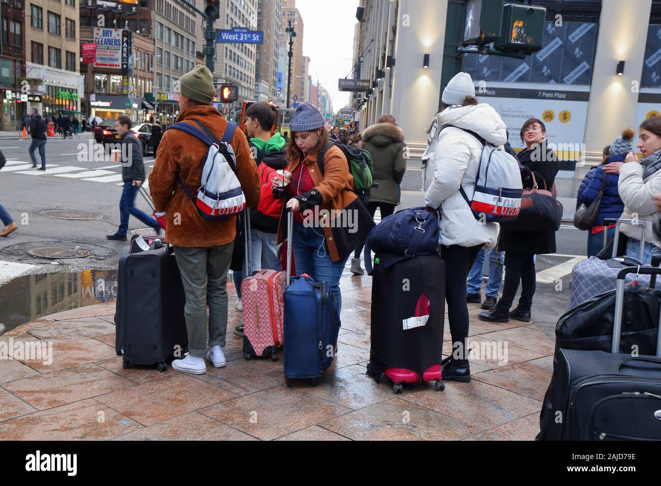 Tourists with rolling suitcases and luggage on a crowded street in