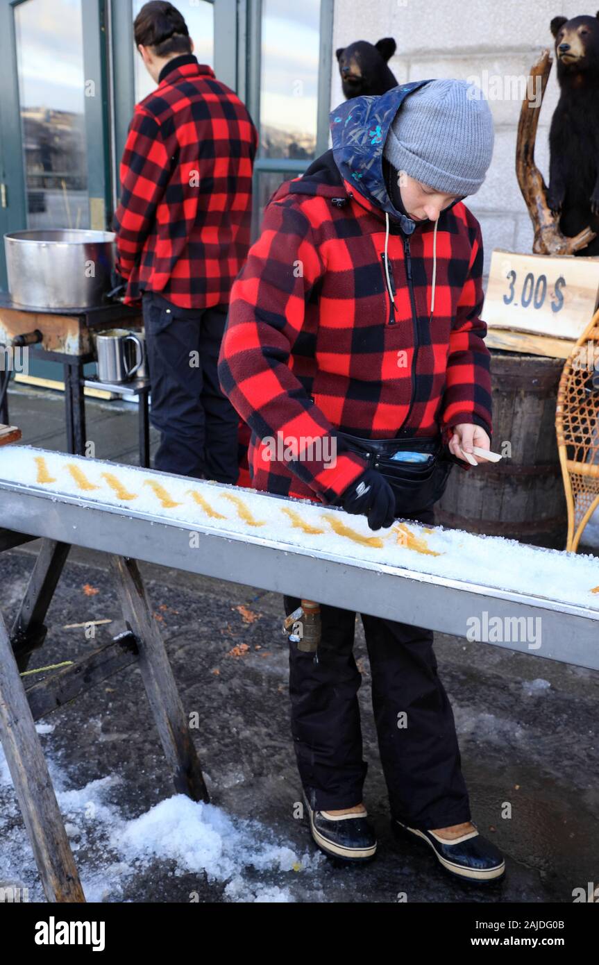 Locals making maple syrup taffy candy on ice for sale on the street of