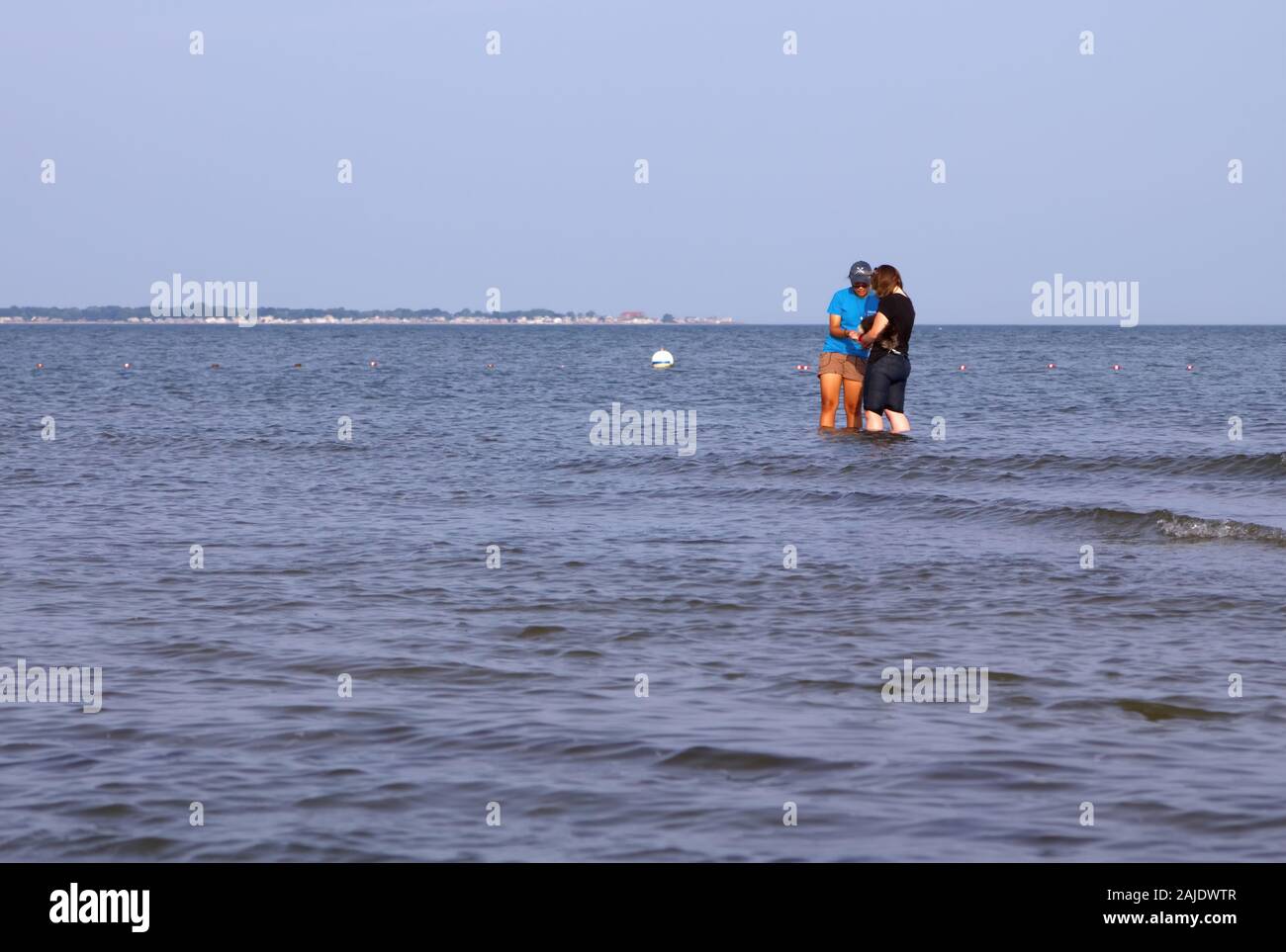 Old Saybrook, CT USA. July 2012. Couple of teenager friends in knee high ocean water by the beach exploring marine life. Stock Photo