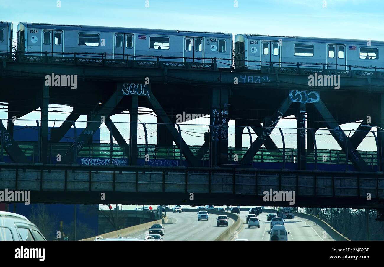 New York City, NY USA. Dec 2019. Metropolitan Transportation Authority train on graffiti laden bridge above the Van Wyck Expressway. Stock Photo